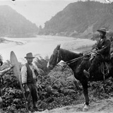 Black and white photograph of 3 men and a horse overlooking the Buller river